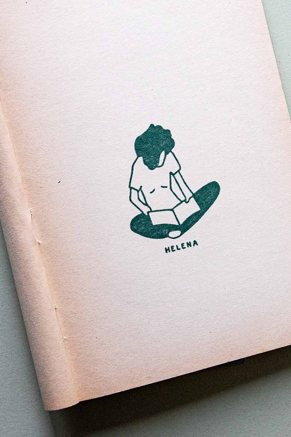 Portadilla de libro estampada con sello exlibris de una persona sentada con las piernas cruzadas leyendo un libro