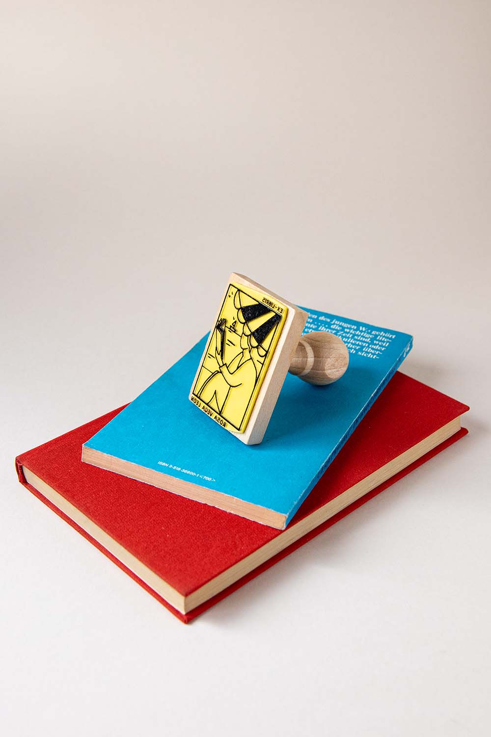 Sello exlibris grabado de una persona leyendo bajo la sombrilla en la playa