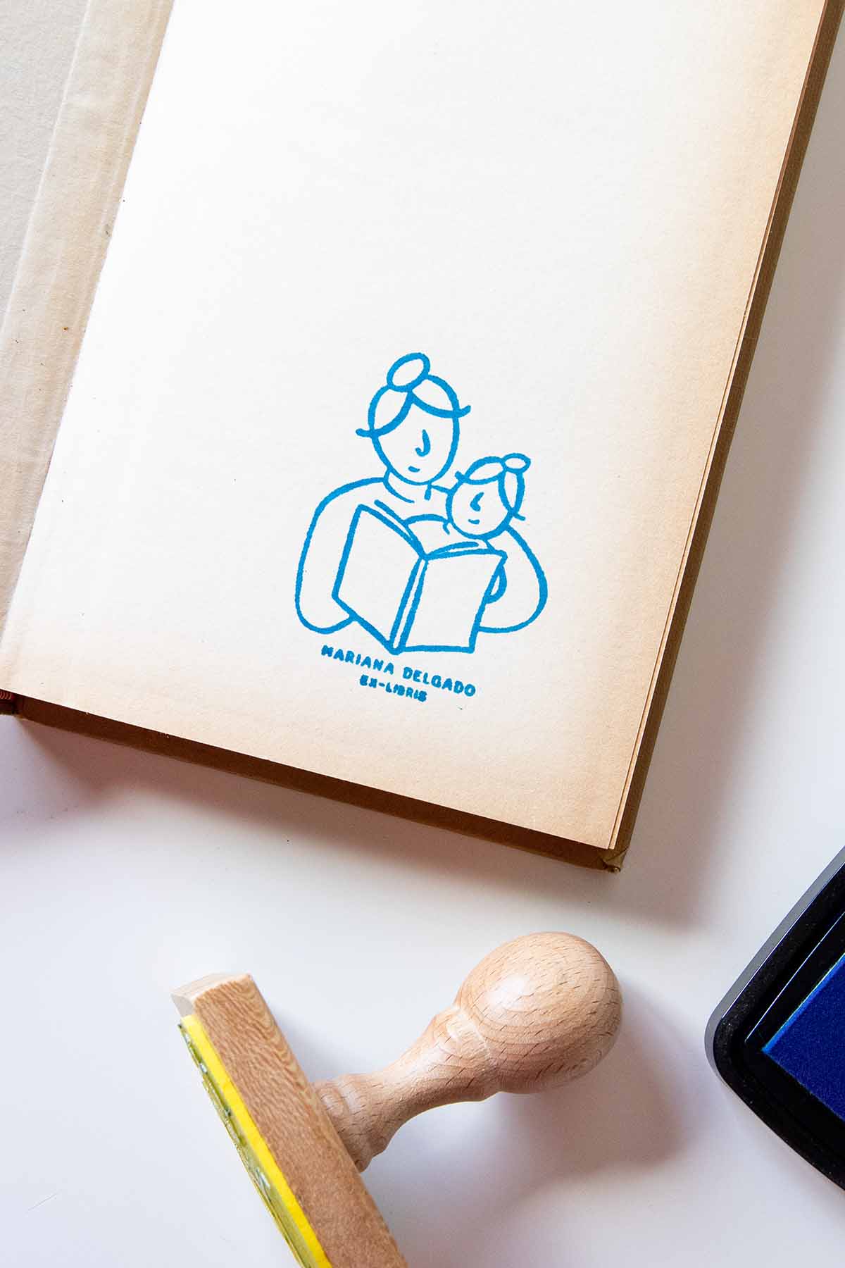 Portadilla de un libro estampada con una madre leyendo a su hija pequeña y sello