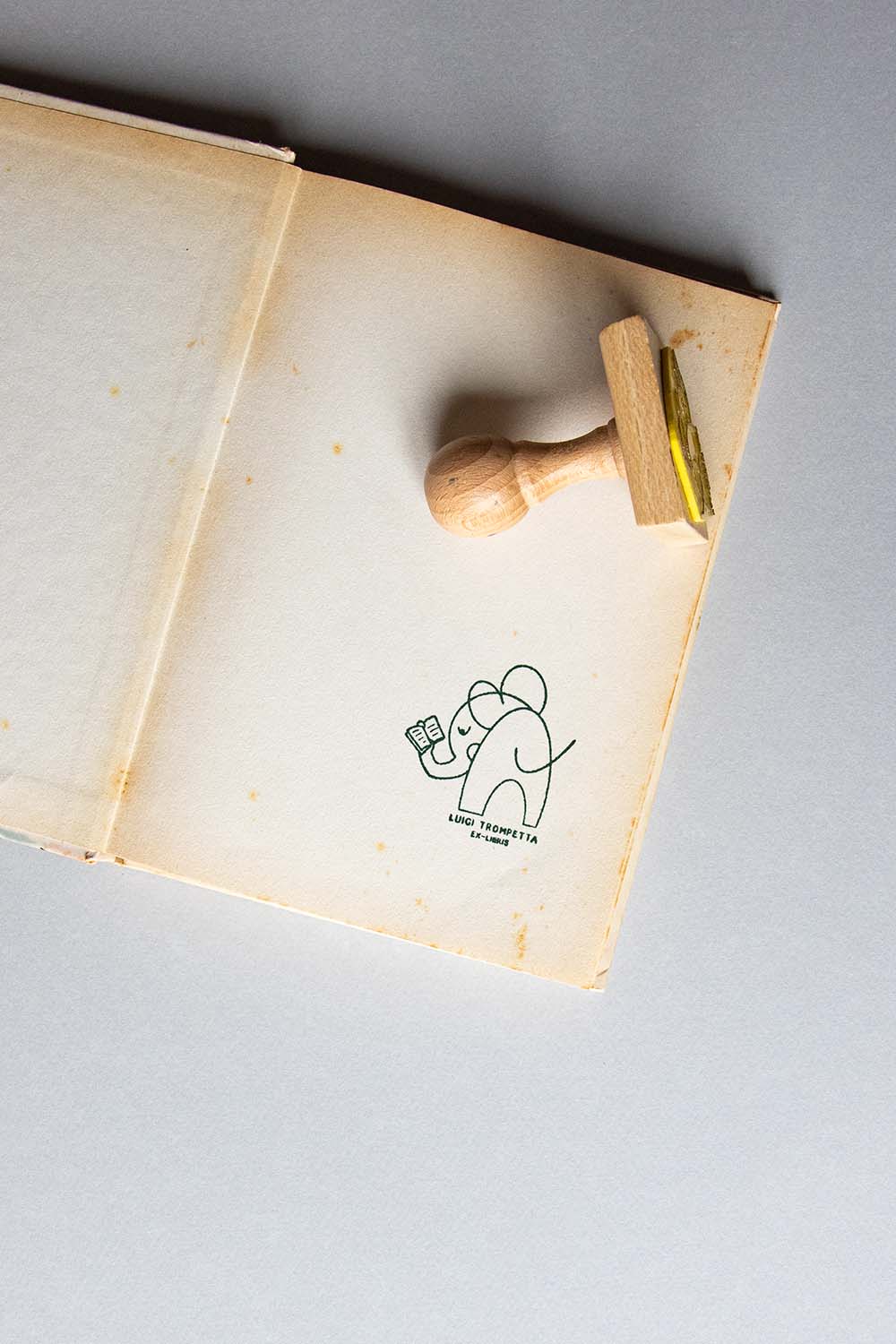 Portadilla de libro estampada con sello exlibris de un elefante leyendo y sello