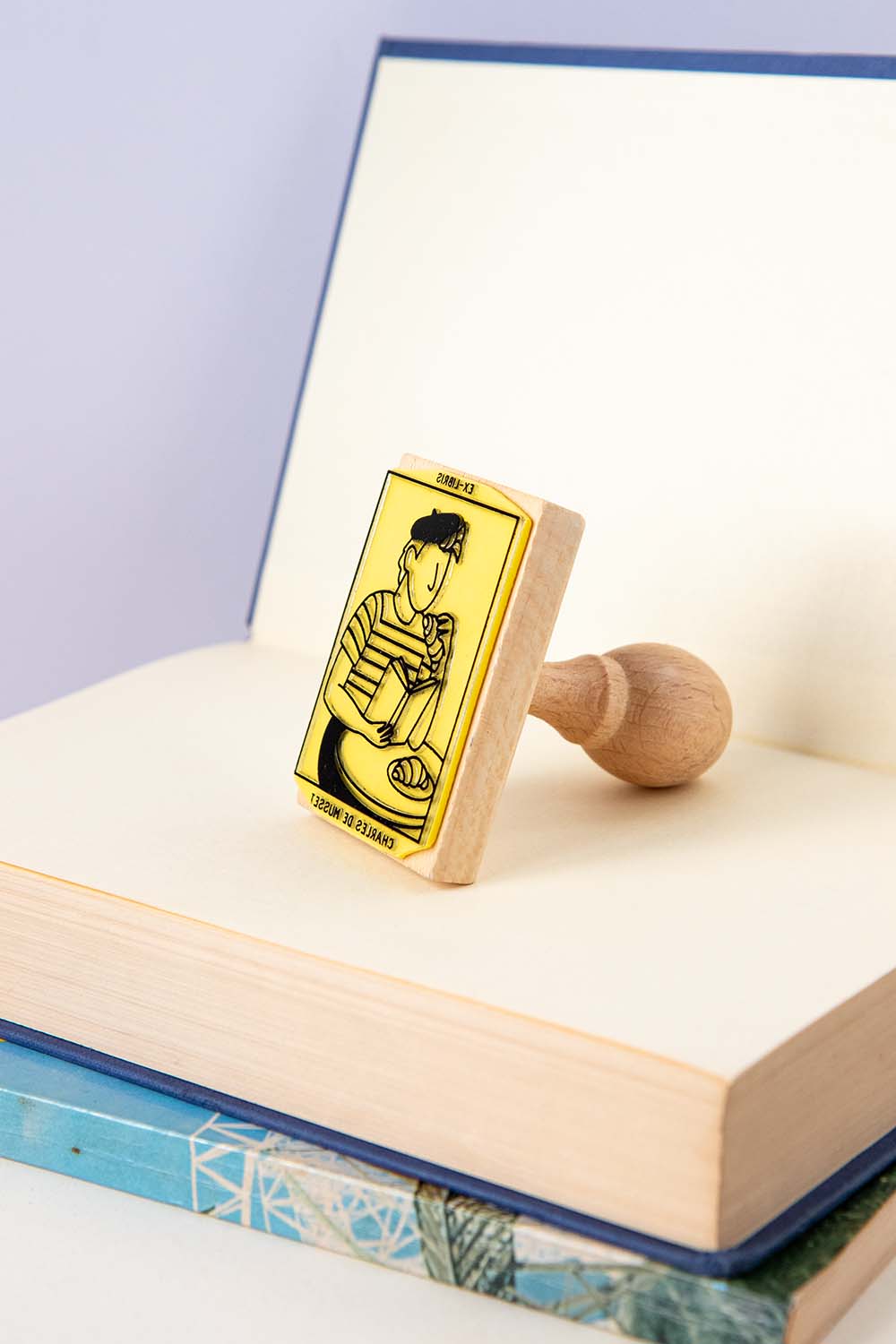 Sello ex-libris con una persona comiendo croissants y leyendo un libro en una terraza de bar parisino