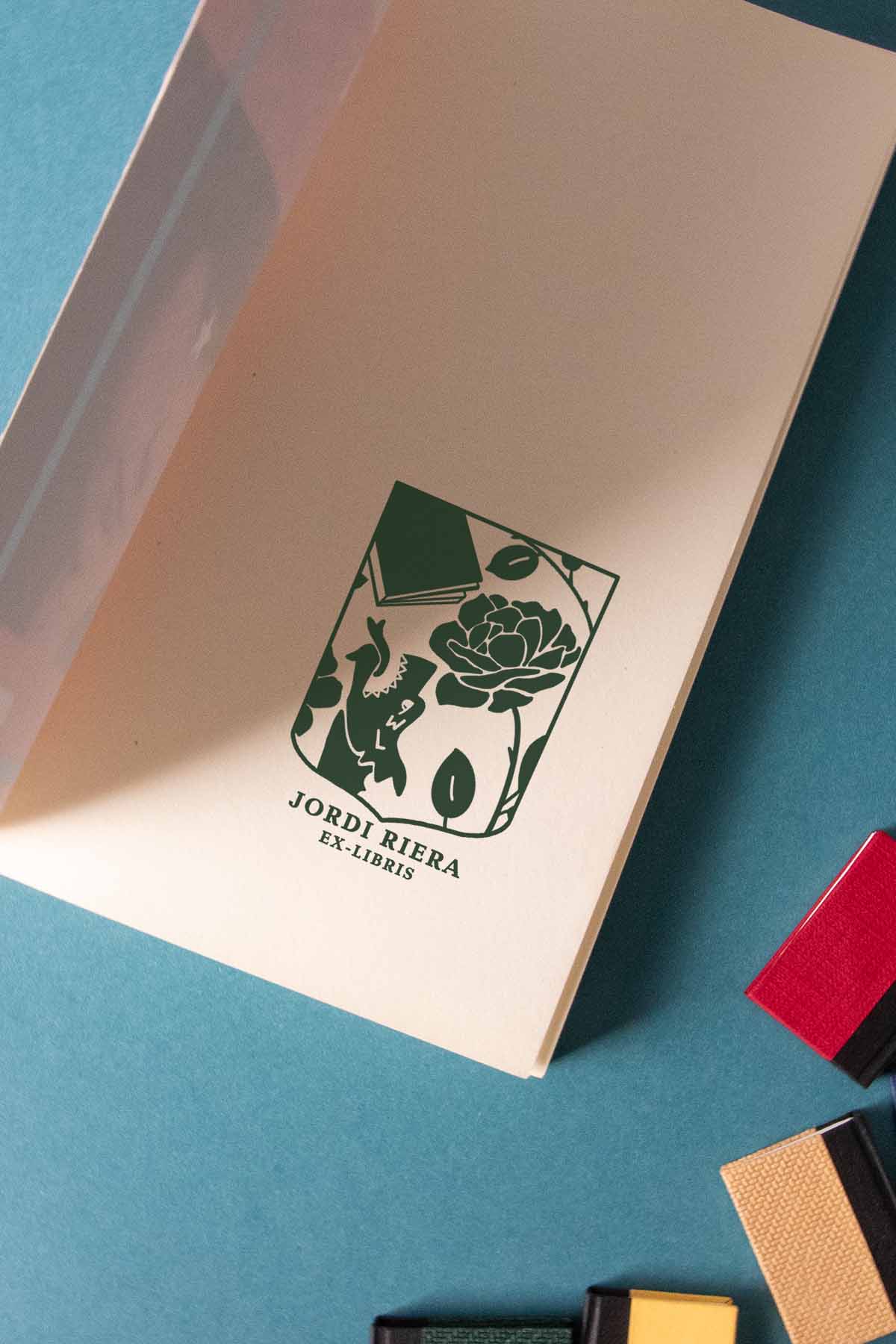 Portadilla de libro estampada con sello exlibris de un escudo con una rosa, un libro y un dragón