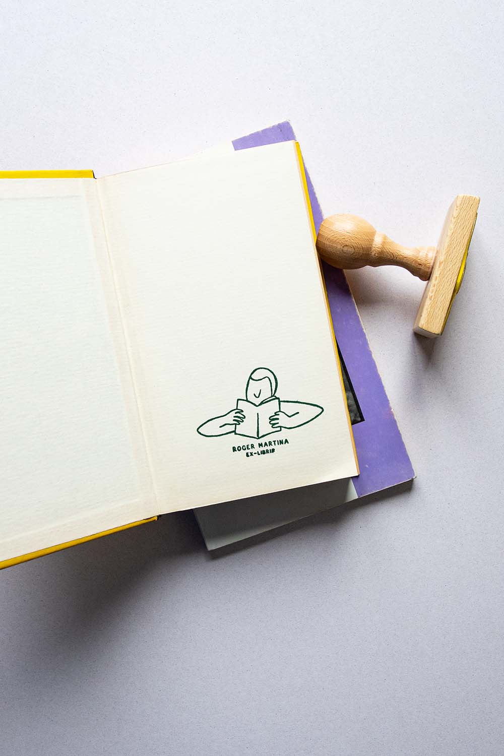 Portadilla de libro estampada con un lector absorto en la lectura de un libro y sello