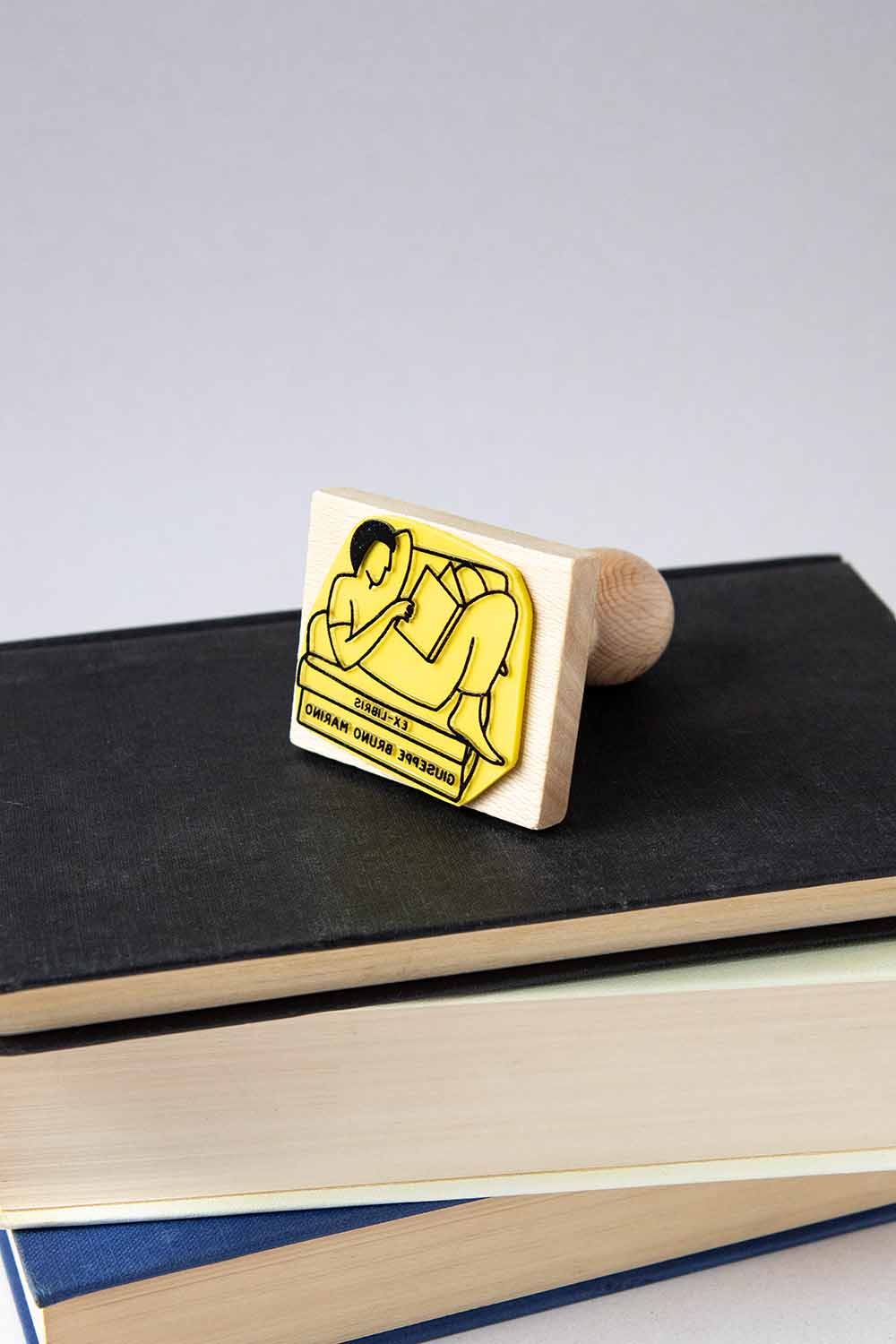 Sello exlibris grabado de un hombre leyendo en un sillón