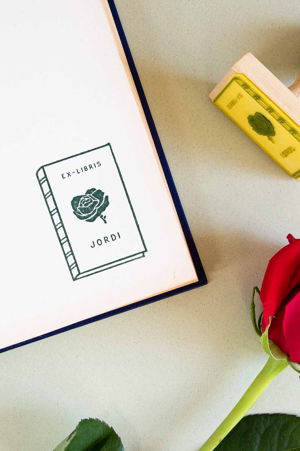 Portadilla de libro estampada con sello exlibris de un libro con una rosa enmedio y sello