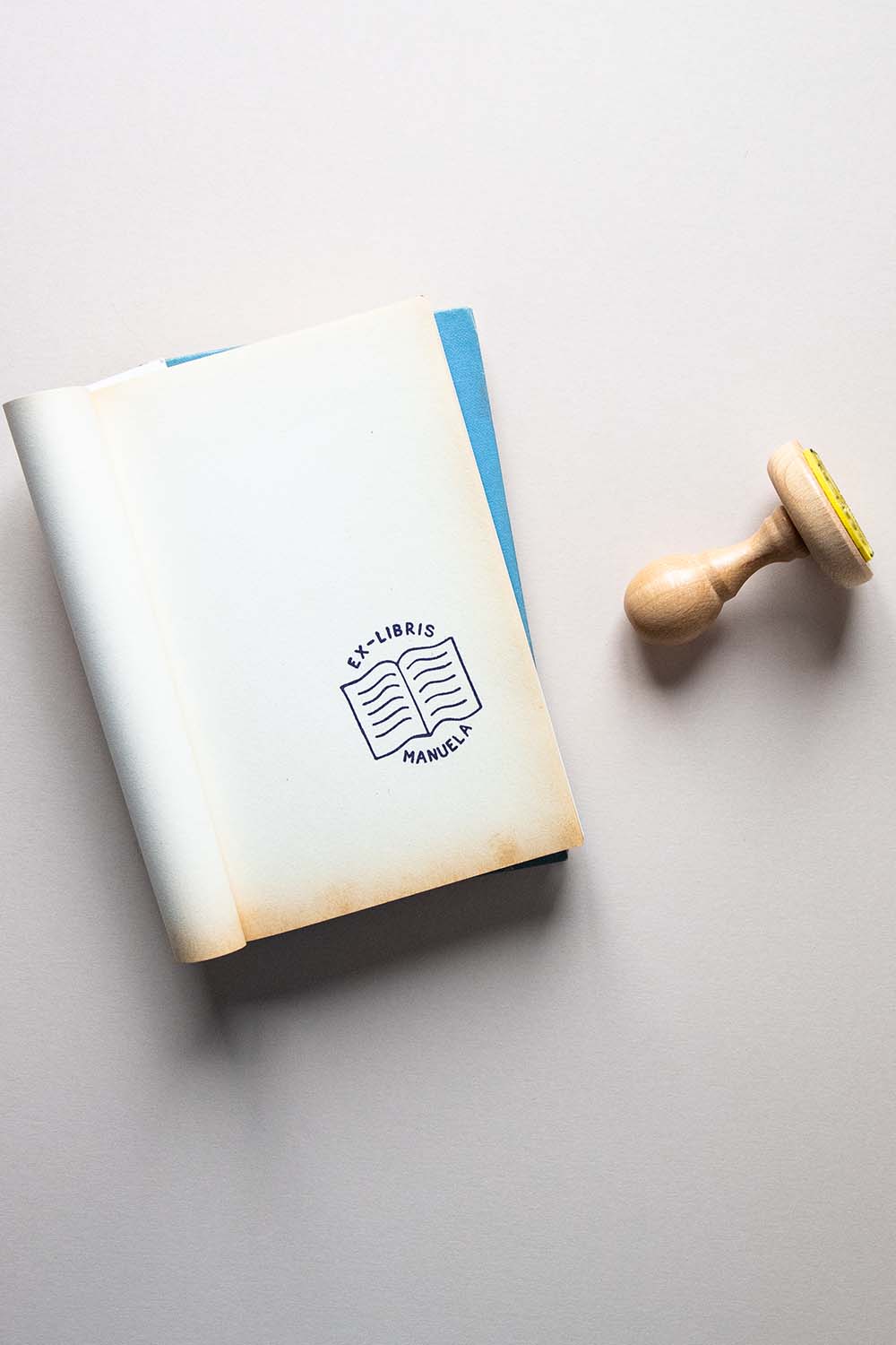 Portadilla de libro estampada con sello exlibris de un libro abierto y sello