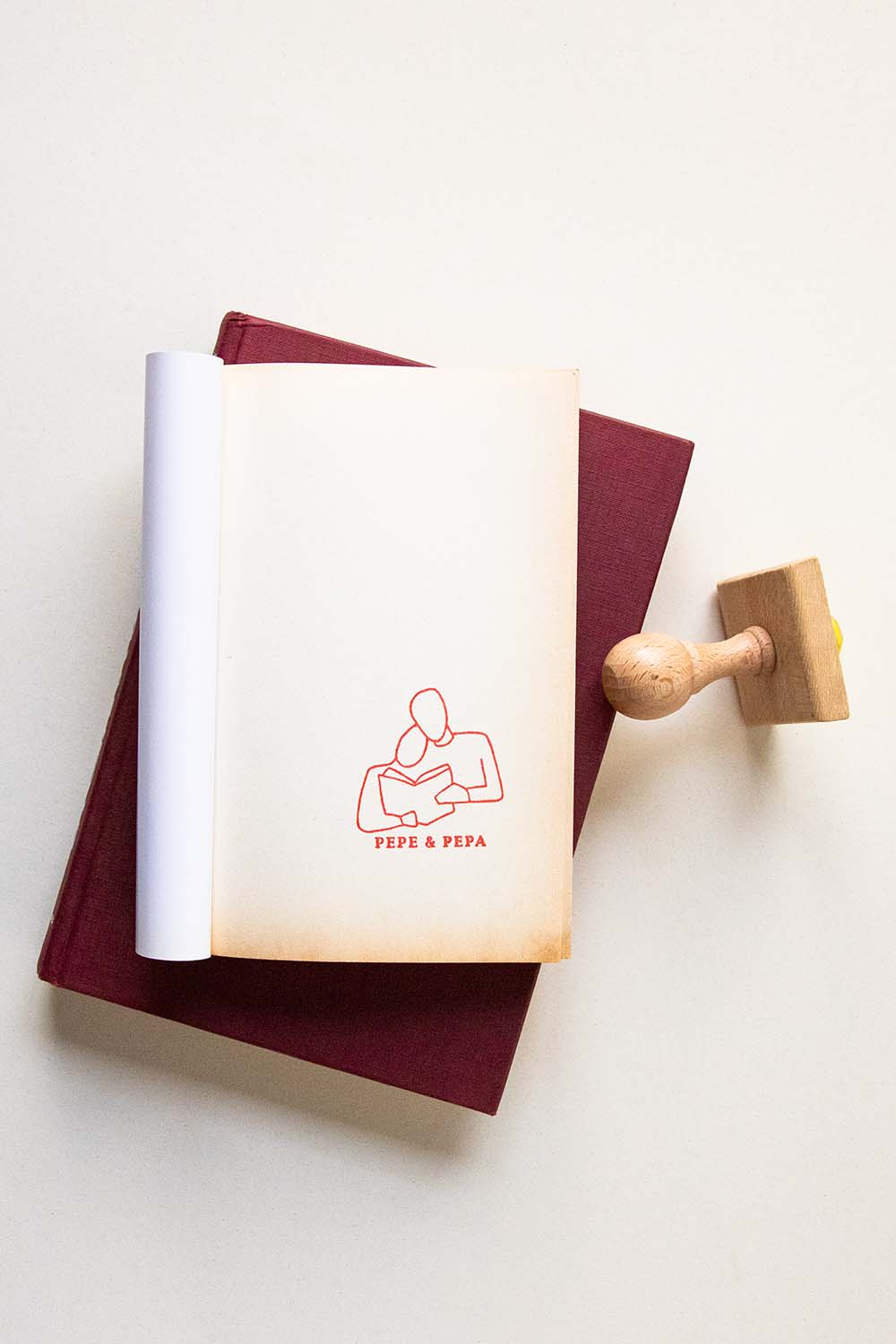 Portadilla de libro estampada con dos personas leyendo juntas un libro y sello