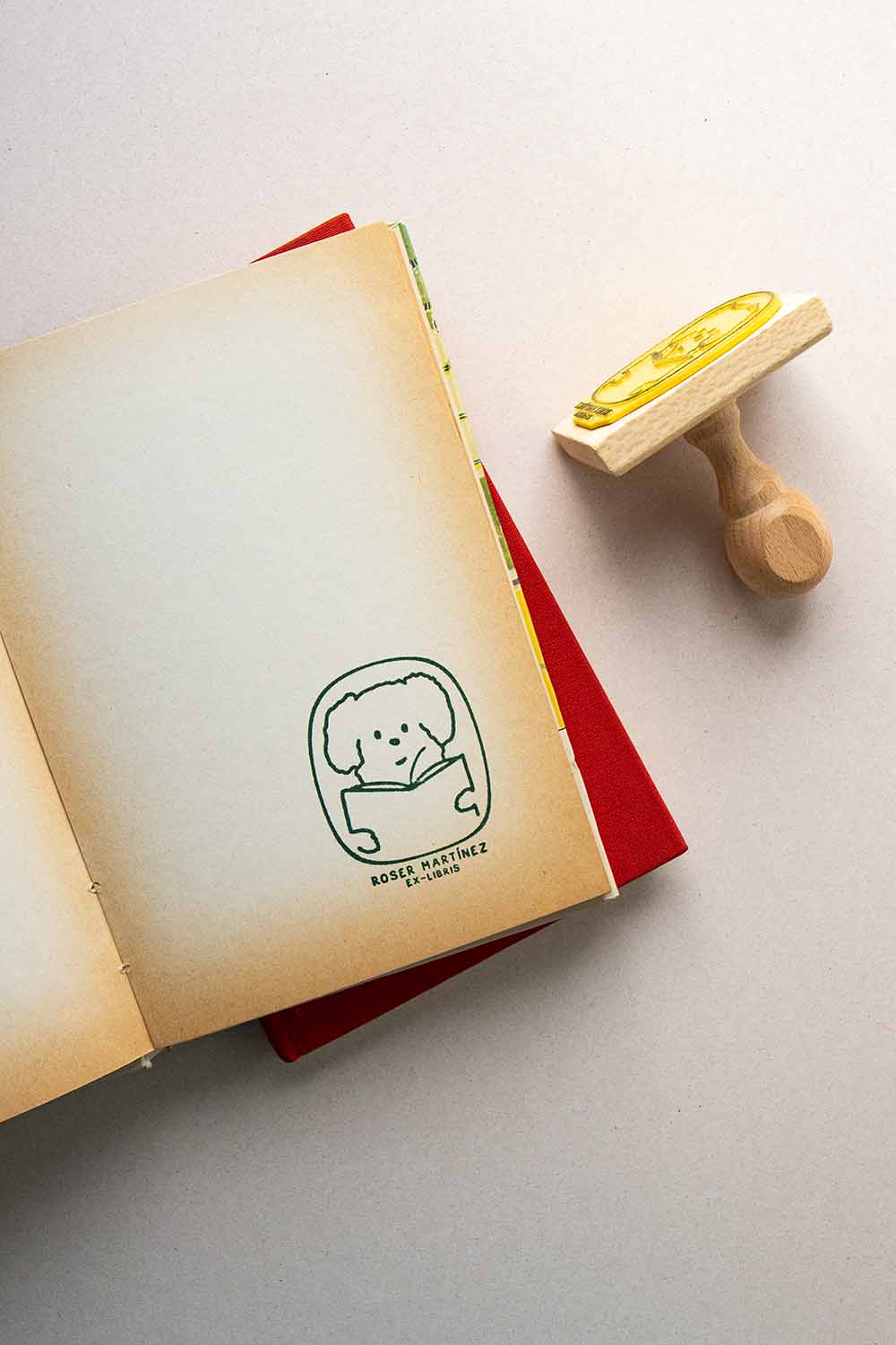 Portadilla de libro estampado con sello exlibris de un perro leyendo y sello