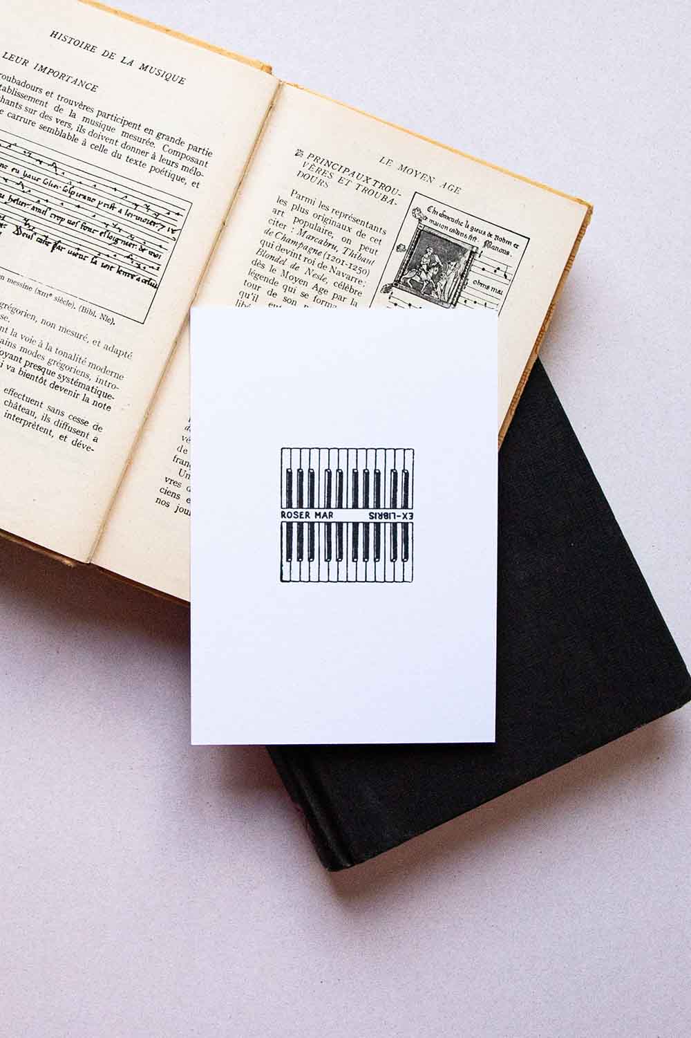 Portadilla de libro estampado con sello exlibris de dos teclados de piano