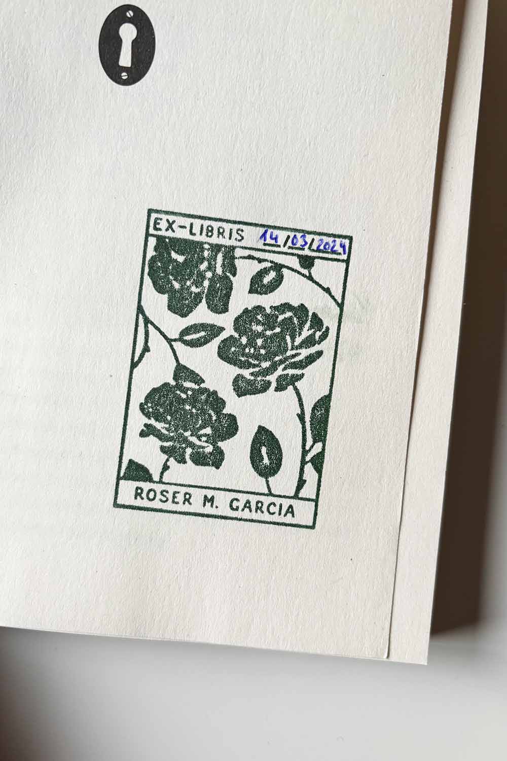Portadilla de libro estampada con sello exlibris de rosas dentro de un recuadro