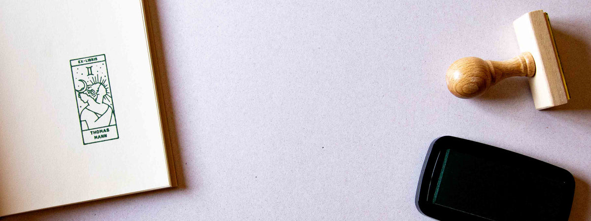Exlibris personnalisé estampé sur la page de garde d'un livre ouvert, avec le signe du zodiaque Gémeaux