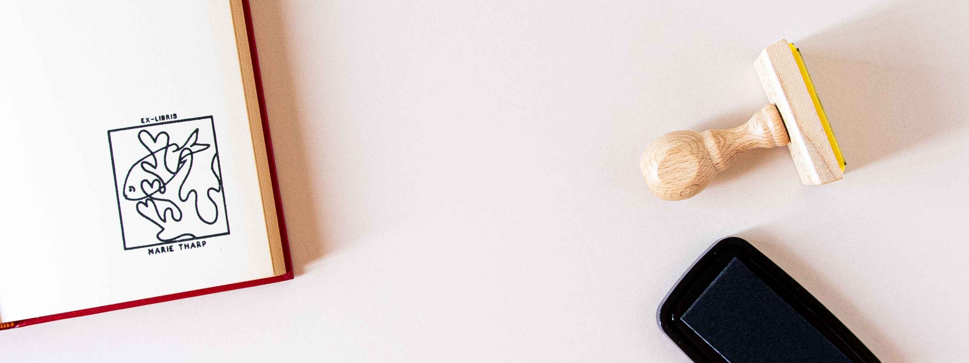 Exlibris personnalisé estampé sur la page de garde d'un livre ouvert, avec un poisson au milieu des coraux